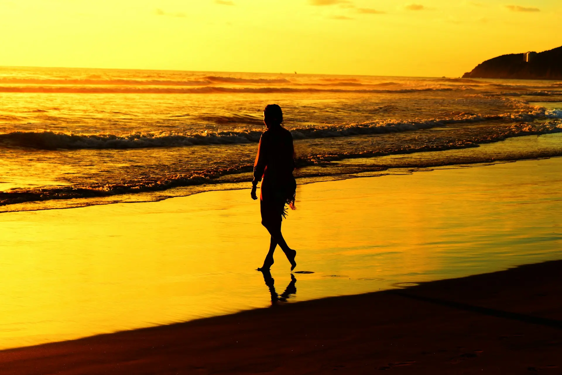 silhouette of man walking on beach during sunset